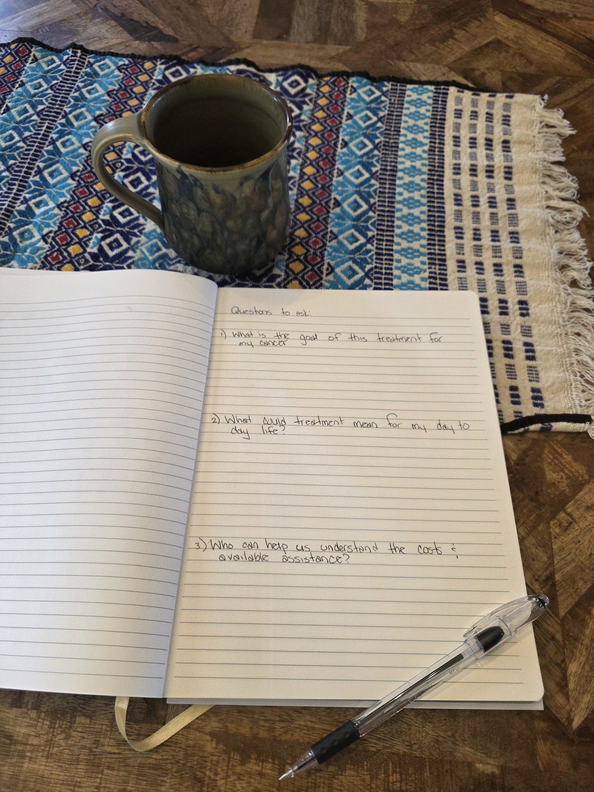 Handwritten list of questions to ask your oncologist about chemotherapy in an open notebook beside a ceramic mug on a woven runner