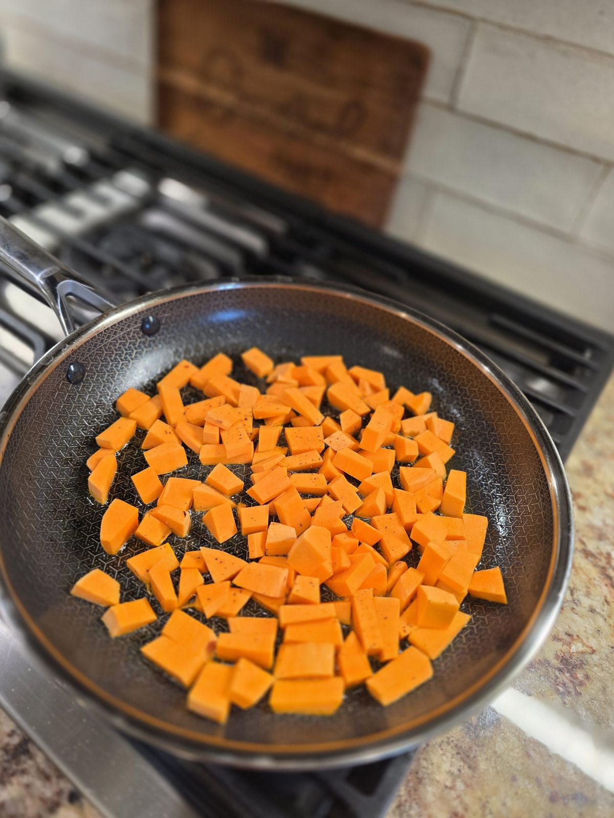 Diced sweet potato starting to cook in olive oil in a skillet on the stovetop