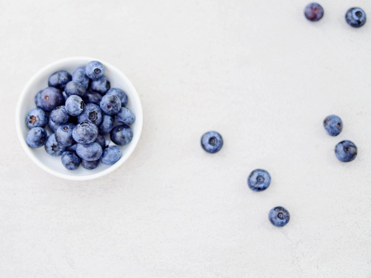 A bowl of fresh blueberries on a light surface