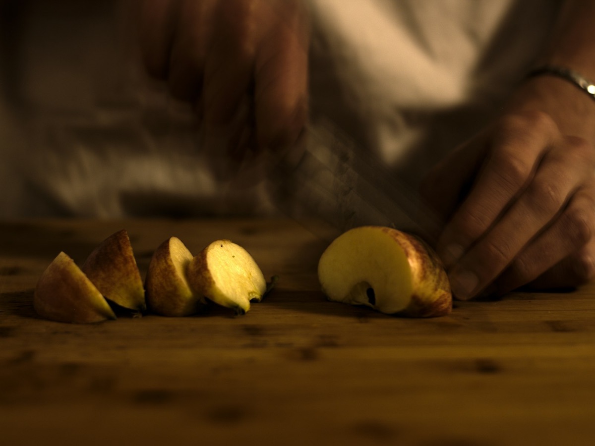 A cut apple beginning to brown on a wooden board