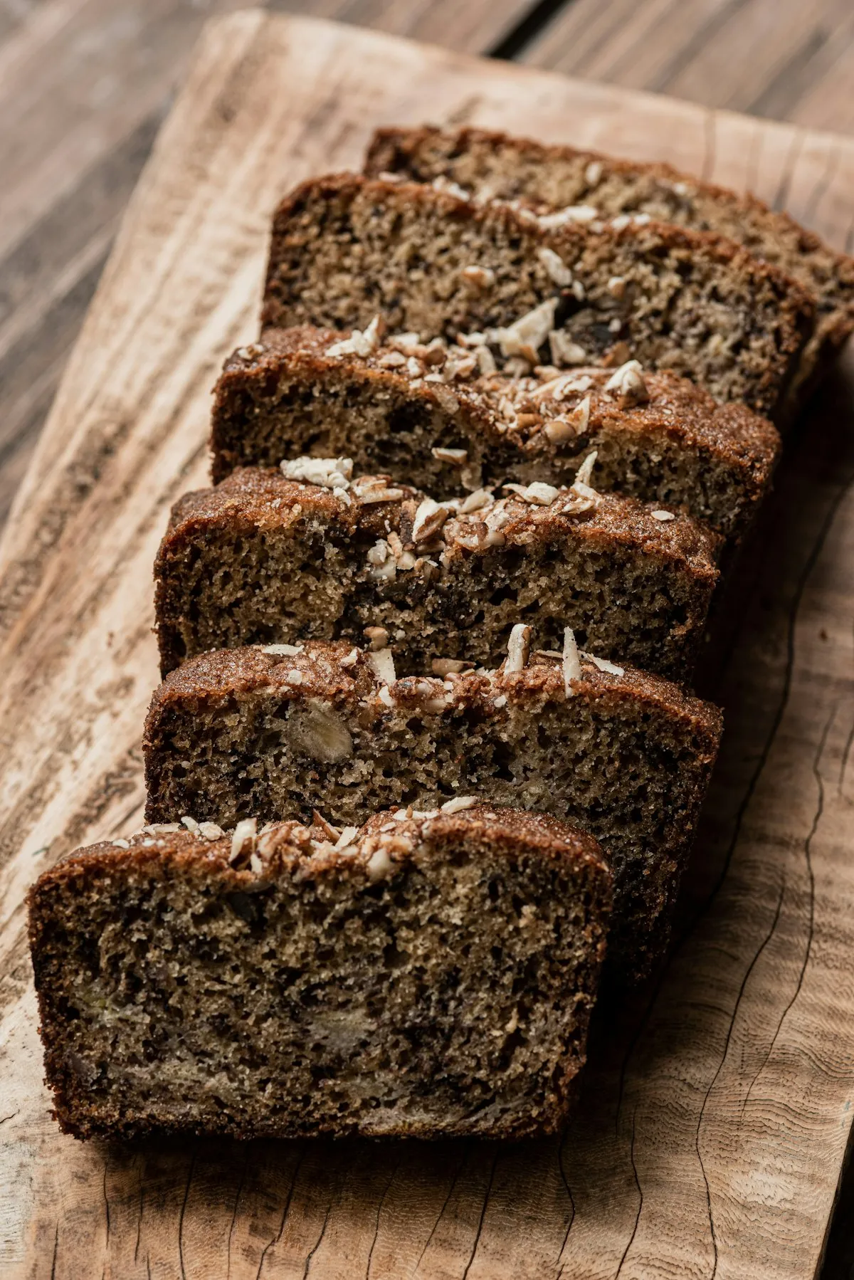 Slices of banana bread with walnuts on a wooden cutting board